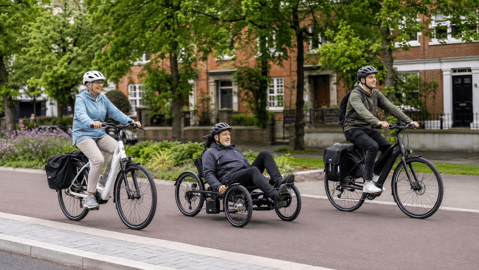 Two people on ebikes, and one man on a mobility electric tricycle between them on a quiet british road