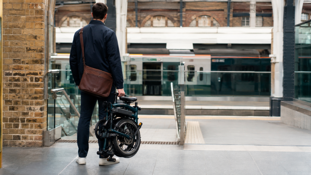 A man waiting for the Tube with his foldable electric bike in his hand